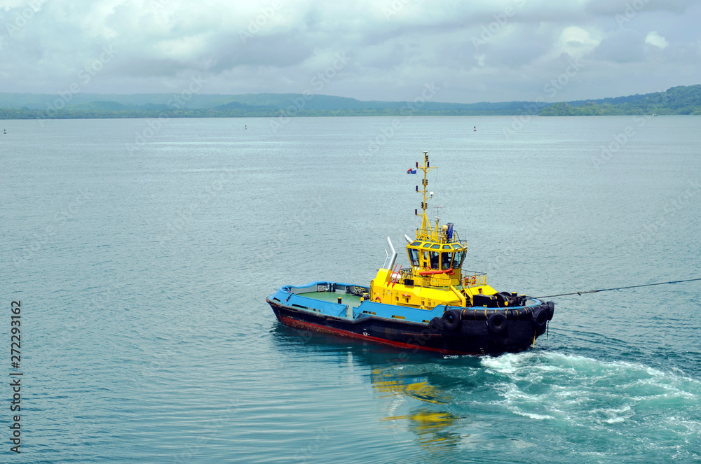 Tugboat assisting to the cargo ship during berthing operation in the port of Cristobal, Panama. Tugboat assisting to the cargo ship during berthing operation in the port of Cristobal, Panama.