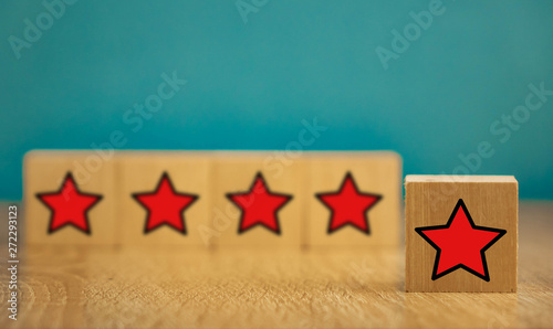 Red stars on wooden cubes on a blue background. Stars mean assessing quality. five-point rating system.