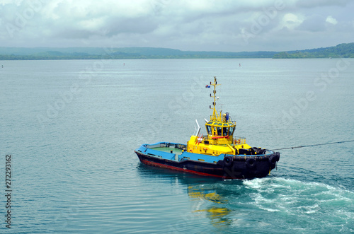 Tugboat assisting to the cargo ship during berthing operation in the port of Cristobal, Panama. 