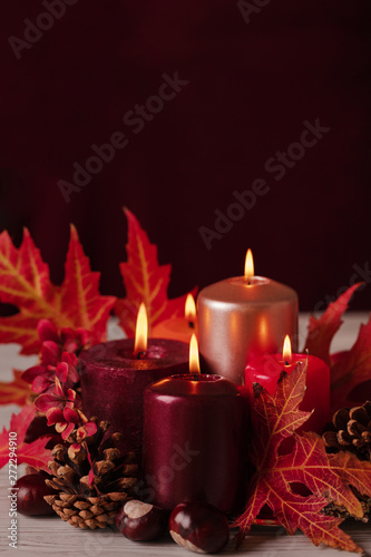 Autumn still life - candles, leaves and cones on the background of pillows.