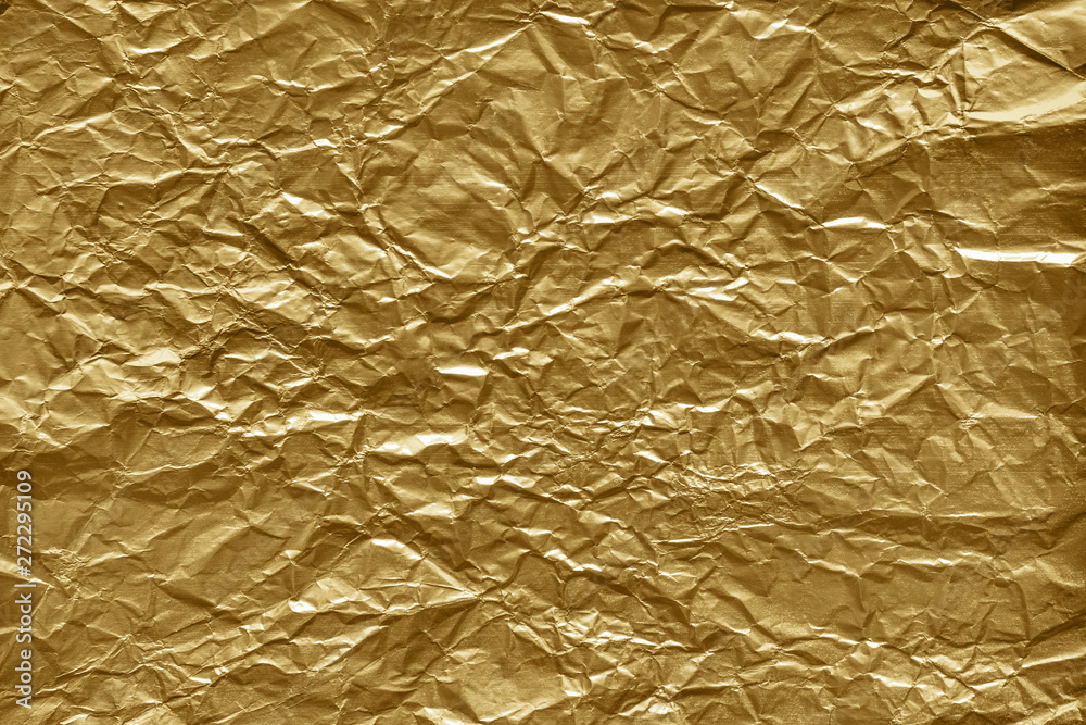 Crumpled gold foil paper texture. Wrinkled shiny metallic surface  background. Stock Photo