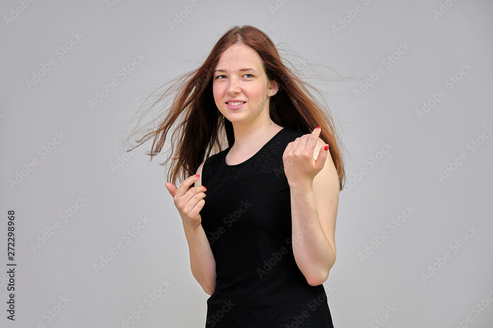 Photo portrait of a beautiful young pretty girl with dark red hair on a gray background in a black jacket. It stands directly in front of the camera in various poses, smiling, happy with life. Photo portrait of a beautiful young pretty girl with dark red hair on a gray background in a black jacket. It stands directly in front of the camera in various poses, smiling, happy with life.