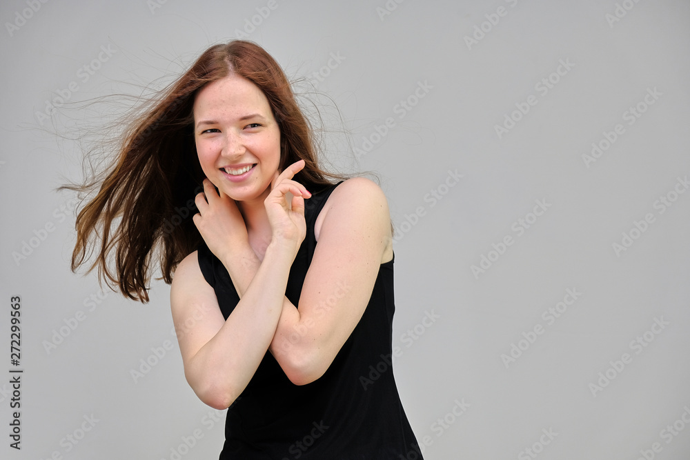 Photo portrait of a beautiful young pretty girl with dark red hair on a gray background in a black jacket. It stands directly in front of the camera in various poses, smiling, happy with life. Photo portrait of a beautiful young pretty girl with dark red hair on a gray background in a black jacket. It stands directly in front of the camera in various poses, smiling, happy with life.