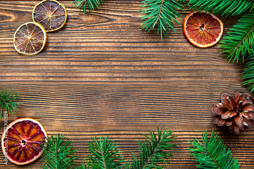 Christmas background, space for text, dried oranges and pice cones on brown wooden table. 