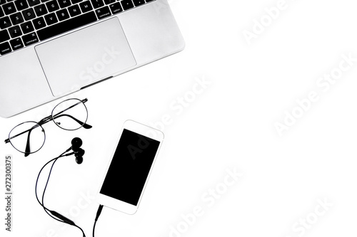 Laptop and devices with mobile phone ,Earphone and vintage glasses on white table Copy space for your text. Top view