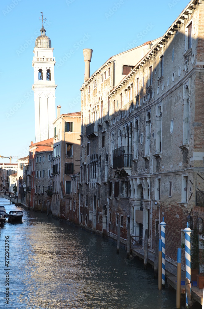 ambiance of a typical Venice narrow water canal, bell tower and old traditional buildings. Italy, Europe.