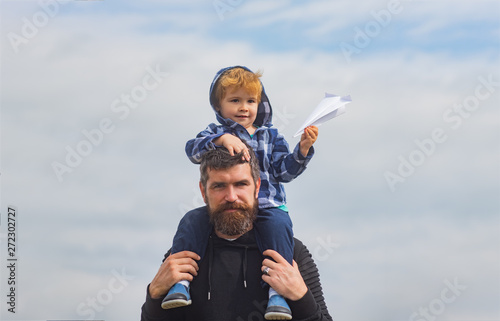 Fathers day. Father and son in the park. Cute boy with dad playing outdoor. Child sits on the shoulders of his father. Father giving son ride on back in park. Imagination.
