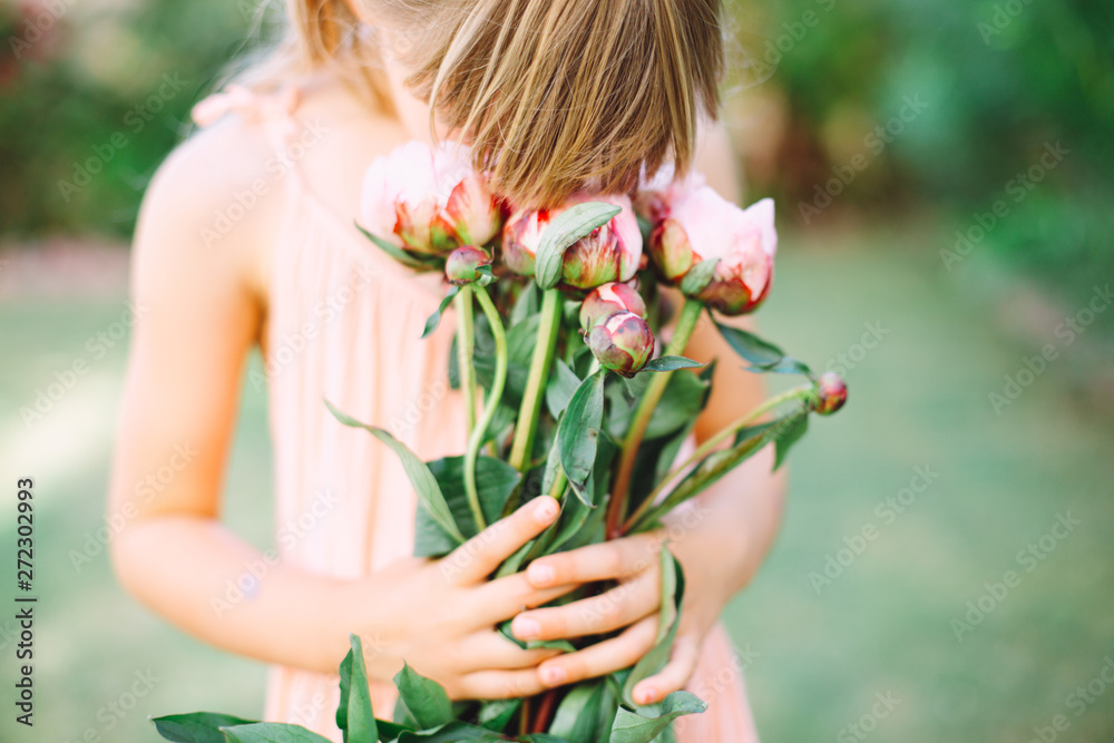 Fototapeta premium Little cute girl holding a bouquet with pink peonies