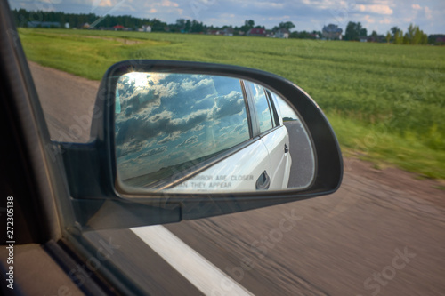 car on the road with motion blur background and rear view mirror. Travel concept. Cloudy sky