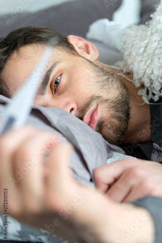 A sick man looks at a thermometer