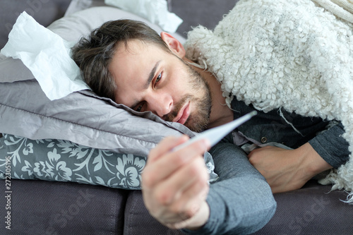 A sick man looks at a thermometer