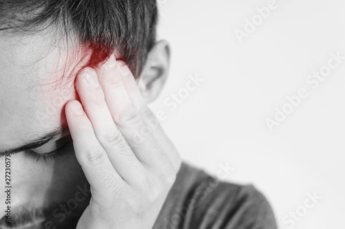 A fit man holding his head in pain, on a white background. Place of pain red dot