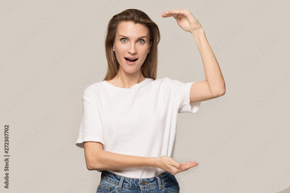 Excited happy young woman showing big size, something tall Excited happy young woman showing big size, something tall