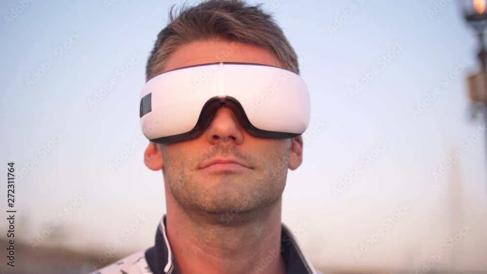 Adult man standing in the center of thecity with relaxing mask on him. New technologies.