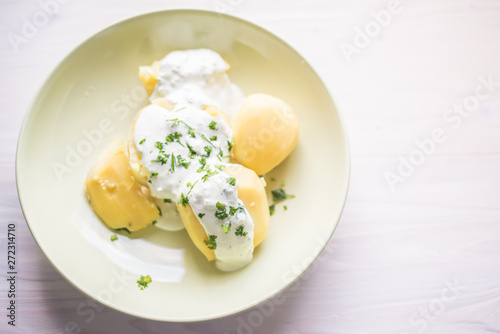 Delicious jacket potatoes. Cooked in water..Nice simple dish with sour cream. Everything on a green plate garnished with herbs.