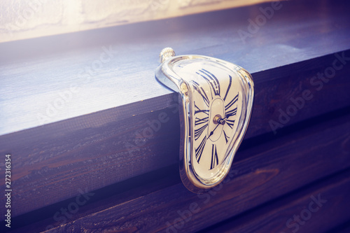 Indoor clocks of unusual shape on a brown wooden background. Time flows