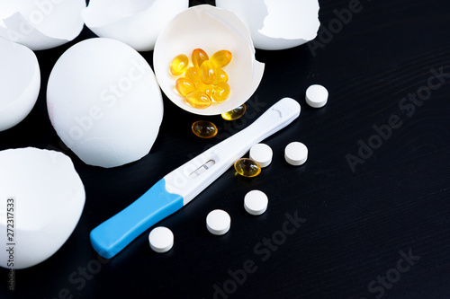 Infertility. Negative pregnancy test and eggshell on black photo