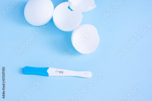 Infertility. Negative pregnancy test and eggshell on blue photo