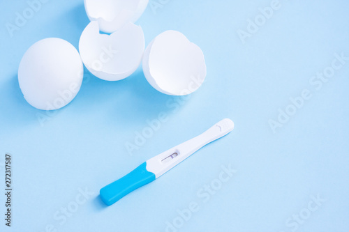 Infertility. Negative pregnancy test and eggshell on blue photo