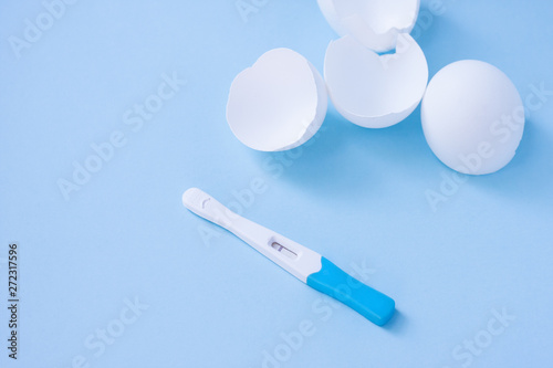 Infertility. Negative pregnancy test and eggshell on blue