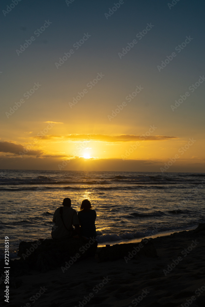 Sunset in paradise two lovers embracing with waves crashing on the beach