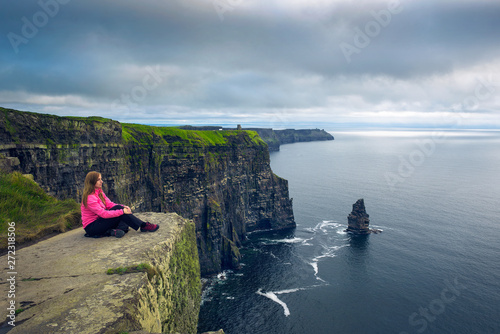 Vászonkép Young woman sitting at the cliffs of Moher