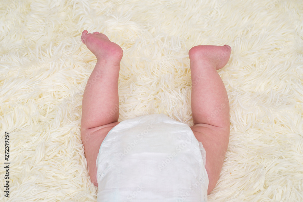 Baby legs and bottom in diaper. Newborn baby sleeping on white. Rear view. Butt in a diaper