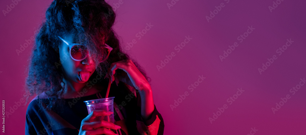 Naughty fashion young african girl black woman wear stylish pink glasses hold drink show tongue look at camera isolated on party purple studio background, banner website design, portrait, copy space - obrazy, fototapety, plakaty 