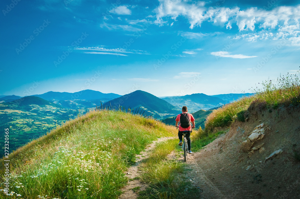 Mountain biker riding through mountains and low hills area landscape