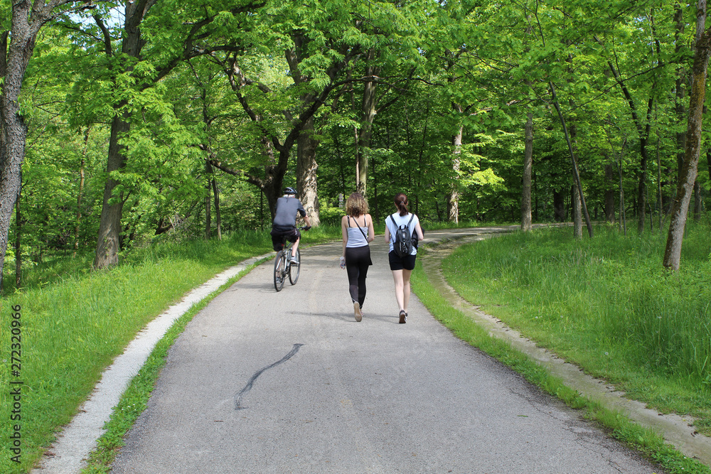 Older man an a bike passing two women on the North Branch Trail in Morton Grove, Illinois Older man an a bike passing two women on the North Branch Trail in Morton Grove, Illinois