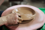 a master ceramist makes plate on a potter's wheel, on a sheet of particle board for better removal and further drying. removal of excess moisture from the product using a foam sponge. reportage.
