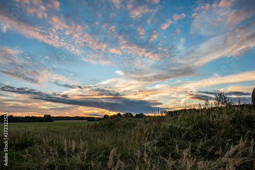 dramatic dark red clouds in sunset over countryside fields and forests