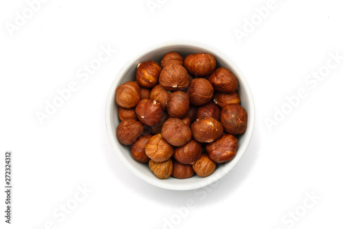 Hazelnut in ceramic bowl on white background, top view