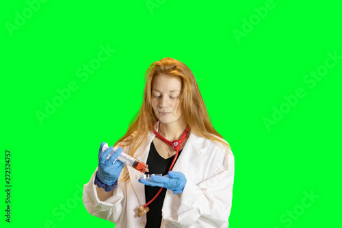 Ginger haired teen girl in lab coat with gloves and stethoscope holding petri dish of colorful liquids.