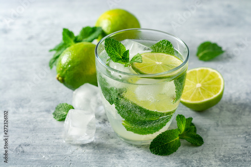 Fresh mojito cocktail with lime and mint in glass on concrete background. Cold refreshing drink. Selective focus.