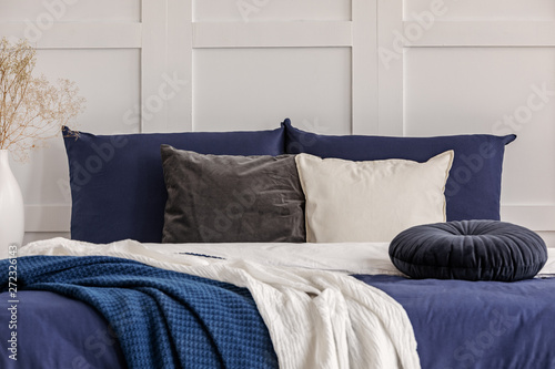 Velvet round pillow on king size bed with blue and white sheets