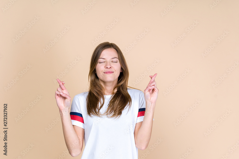Front view of young adult woman with closed eyes crossed fingers on two hands Front view of young adult woman with closed eyes crossed fingers on two hands
