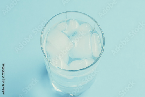 Refreshing cold Water with ice in a glass on a blue background. Concept of thirst, heat, refreshment in the summer. Flat lay, top view