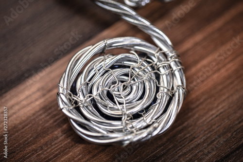 Spiral shape silver jewelry on wooden background. Silver Pendant