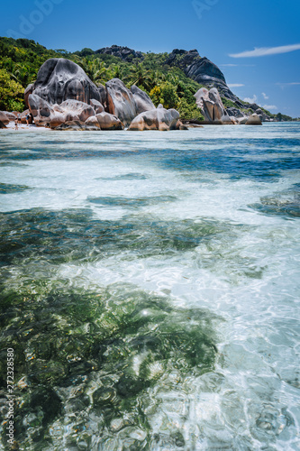 Shallow water with algal plants in front of unique Anse Source D'Argent tropical beach, La Digue Seychelles. Luxury exotic travel concept photo