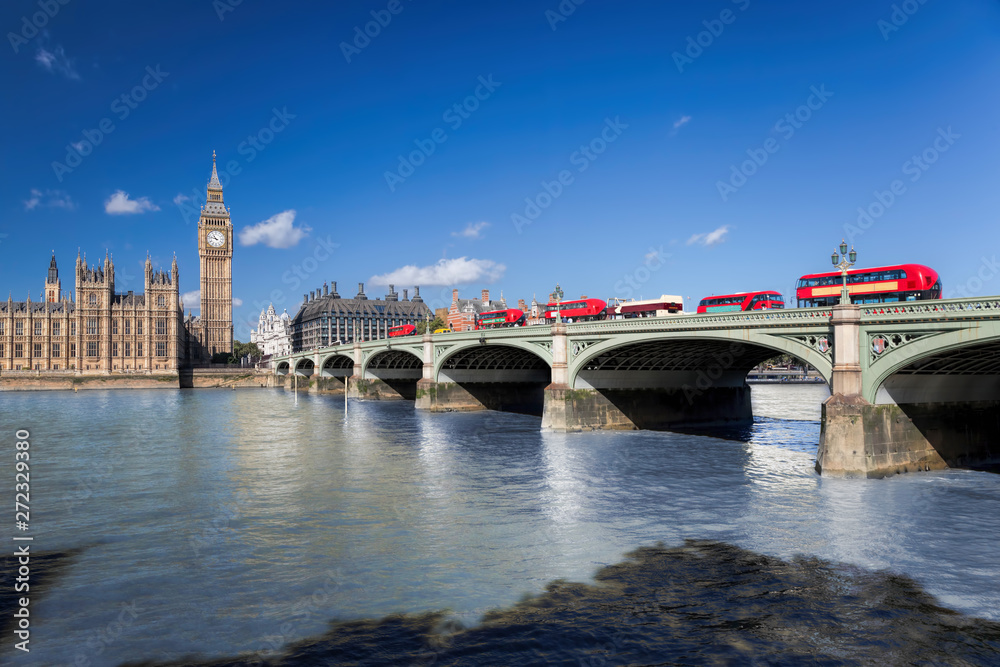 Big Ben and Houses of Parliament with red buses on the bridge in London, England, UK