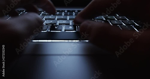 User typing on a laptop keyboard at night - hacker, it specialist, coding concept footage