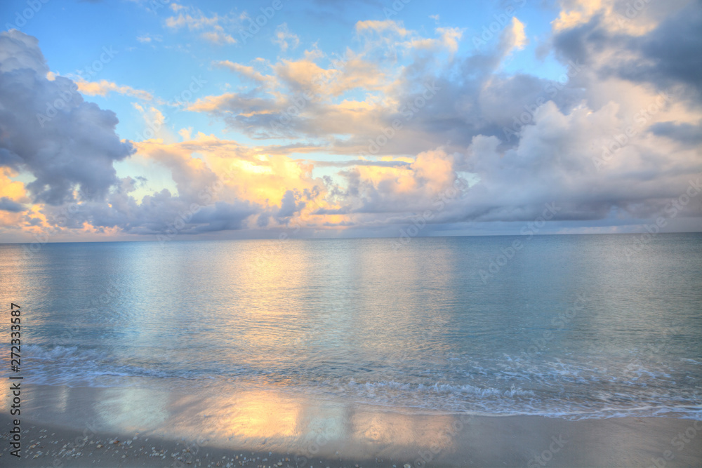 Ocean rolls in under puffy clouds on North Naples Beach at sunrise