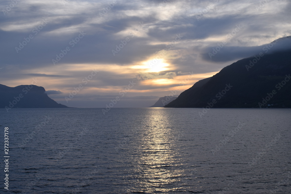 Sunset on a Norwegian fjord. Scandinavian cruise view. Sun reflection in water. Sunset on a Norwegian fjord. Scandinavian cruise view. Sun reflection in water.