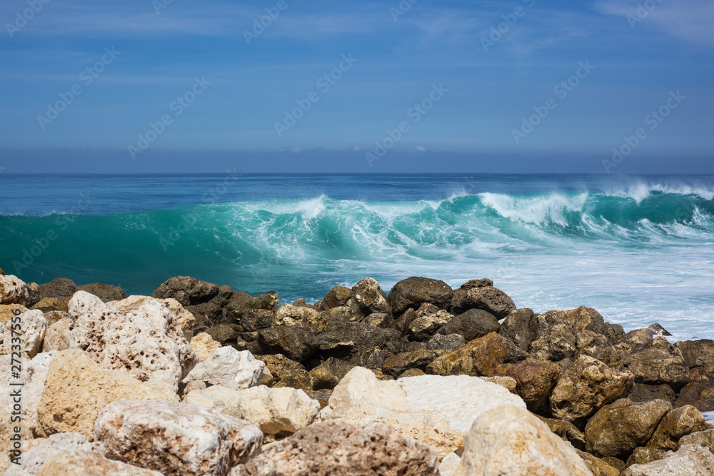 sea view. blue ocean, big waves, black and white stones, high tide