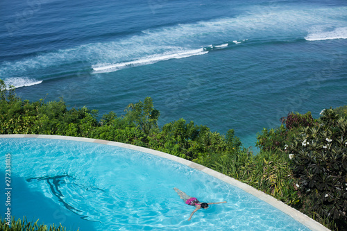 top view of the infinity pool and blue ocean. sunny hot day, tropics. woman swims underwater