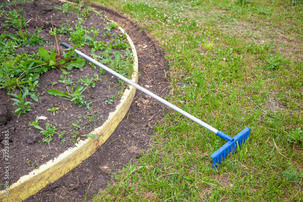Garden care. Tools in the garden. Rakes and flower bed with flowers. Work on the ground. Stock