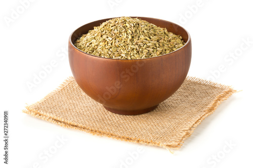 Dried fennel seeds in wooden bowl over white background