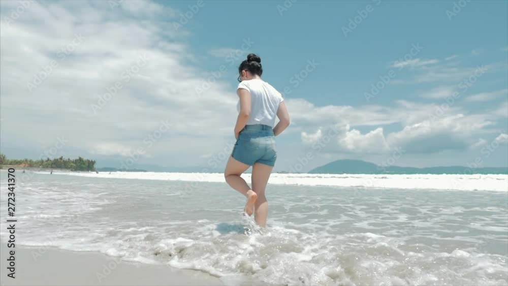 On a Tropical Beach Beautiful Scene of a Woman Walking on Ocean Beach at Sunset. Close-Up of Women's Legs European Beautiful Brunette, Walking Along the Beach, Slow Motion.