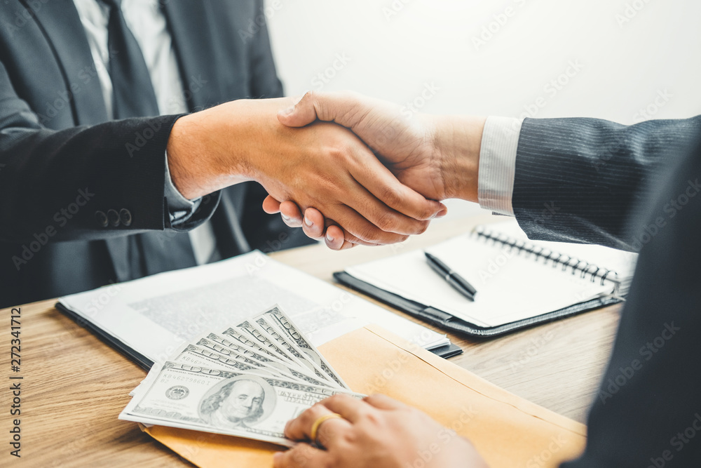 Corruption concept,Business man passing money dollar bills corruption bribery to businessman manager and handshake between two colleagues.